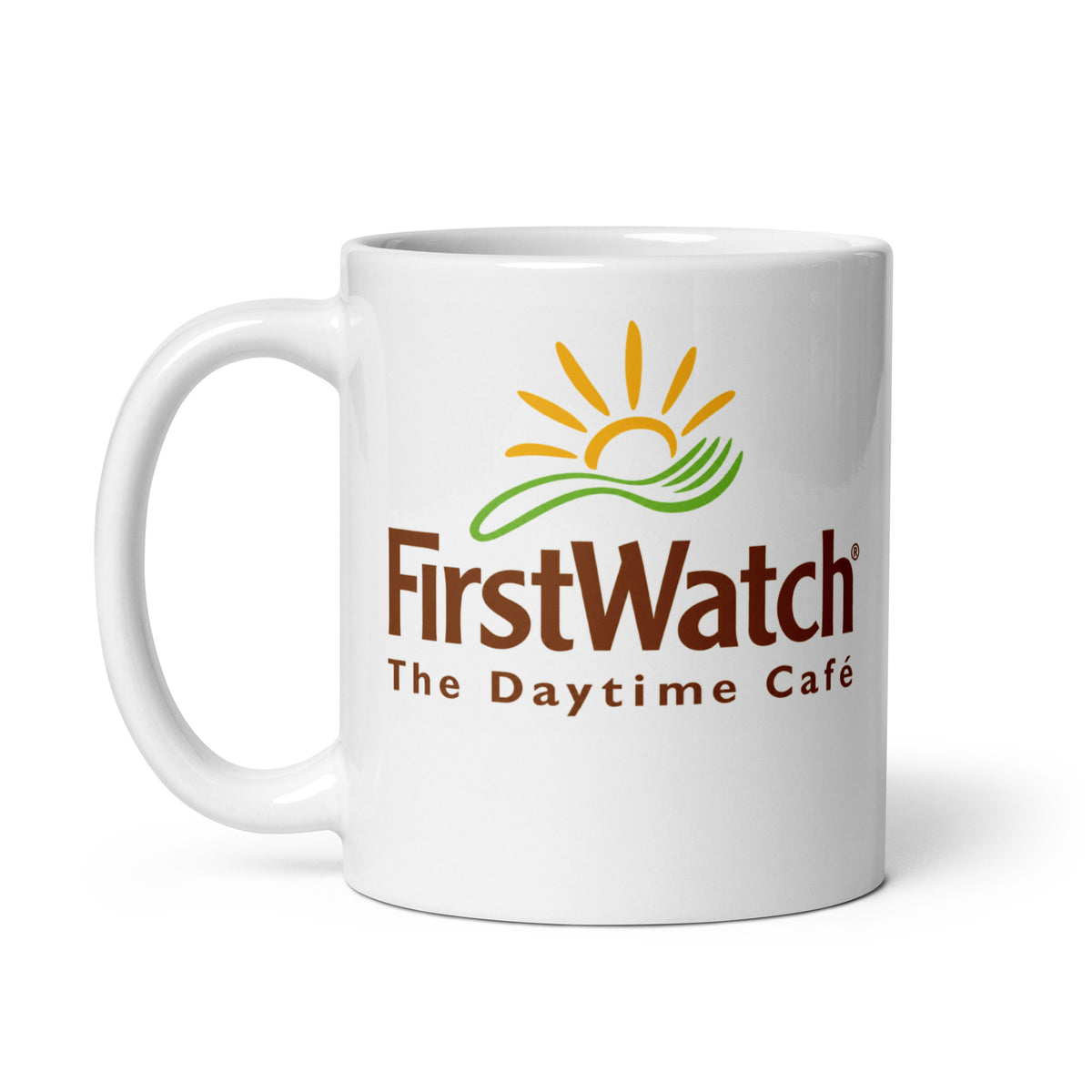 First Watch logo coffee mug featuring brown lettering, yellow sunrise and green design on a white ceramic cup with matching handle